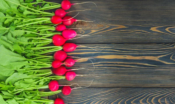 Büyük bir demet taze turp koyu tahtalarda, yakın plan.