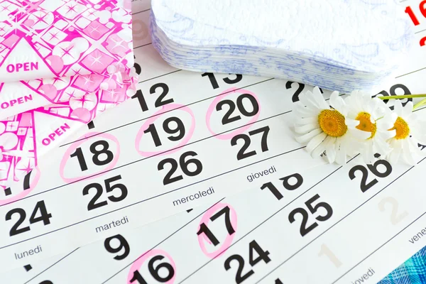 Санитарные прокладки, календарь, полотенце и розовый цветок на светлом фоне — стоковое фото