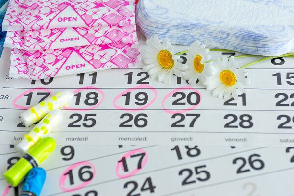 Woman hygiene protection , calendar close up.menstruation with cotton swabs , white daisies, Sanitary napkins on a light background