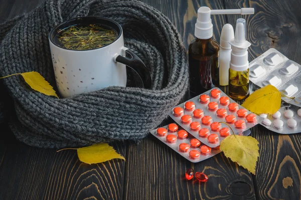 Sonbahar ve sağlık. Soğuk - çay, termometre ahşap arka plan üzerinde hap