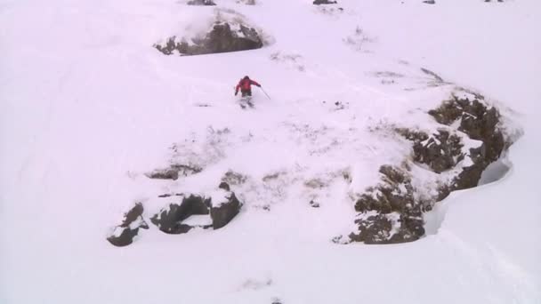 Esquiador saltando desde un acantilado pasa por la cámara — Vídeo de stock