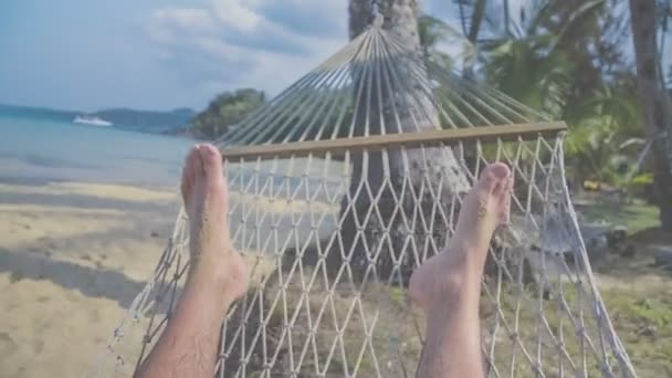 Voeten swingen in een hangmat, Pov. Ontspannen op het strand met uitzicht op zee — Stockvideo