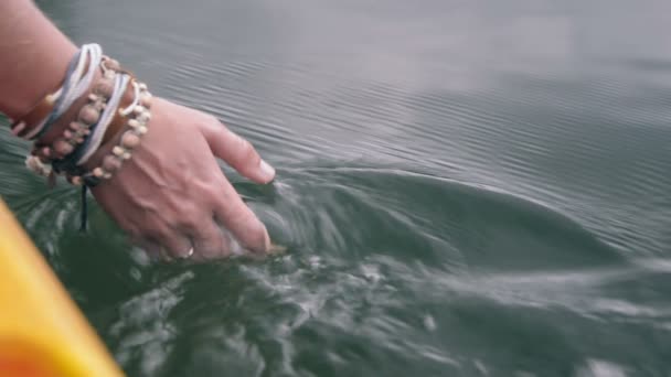 Mano femenina con pulseras toch superficie de agua — Vídeo de stock