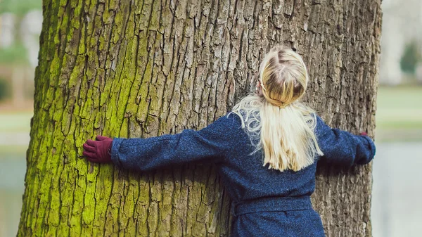 Rückansicht eines Mädchens mit lockigem Haar, das einen Baum umarmt — Stockfoto