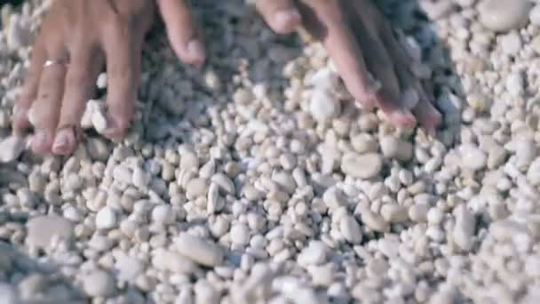 Manos de mujer sosteniendo y relase piedras pequeñas en manos sobre fondo de piedra de playa — Vídeo de stock