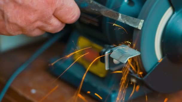 Grinding of wedge grinding wheel is rotating, orange sparks are flying, part of grinding machine, piece of metal and grinded line are in the frame — Stock Video