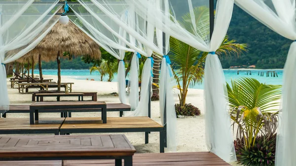 Beach bed on white sand among palm trees in full sun — Stock Photo, Image