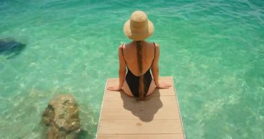 Hırvatistan 'ın Makarska kentinde yaz mevsiminde limanda turkuaz deniz manzarası seyreden genç bir kadın görülüyor.