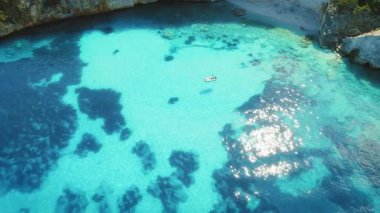 Kefalonya 'nın kayalık kıyılarında sığ turkuaz sularda yüzen tekne Yunanistan' da.