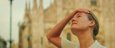 Altın saat boyunca Milano Duomo Meydanı 'ndaki katedral yakınlarında mimariye hayran olan kadın.