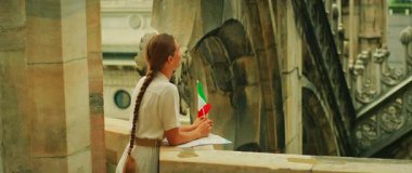 İtalyan bayrağı taşıyan kadın Duomo di Milano Katedrali mimarisine bakıyor..