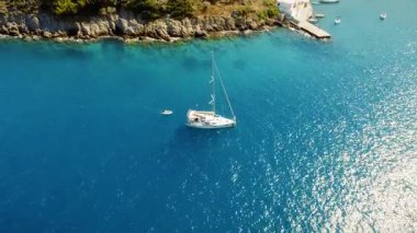 Yelkenli, engebeli Akdeniz kıyısının yanındaki sakin, derin mavi bir körfeze demir attı..