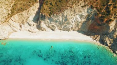 Engebeli uçurumlar ve bereketli yamaçlardaki bitkilerle dolu altın plaj yaz güneşli bir günde..