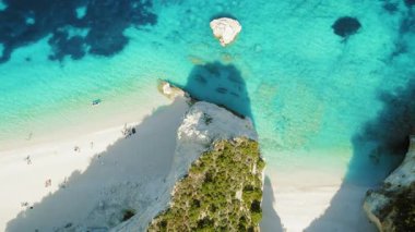 Yunanistan 'ın Kefalonia kentinde güneşlenen insanlarla beyaz kumsal ve turkuaz deniz manzarası.