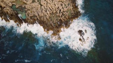 Yunanistan 'da yaz aylarında engebeli kayalık kıyılara çarpan deniz dalgalarının hava manzarası.