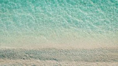 Yunanistan 'da kristal berrak turkuaz su ve pürüzsüz kumlu kıyı şeridine yakın çekim.