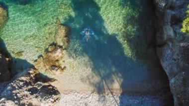Kefalonya 'daki kayalık sahil yakınlarında sığ turkuaz sularda yüzen yüzücü Yunanistan.