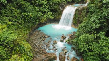 Kosta Rika ormanında şelalenin altındaki turkuaz havuzun yanında duran kadın..