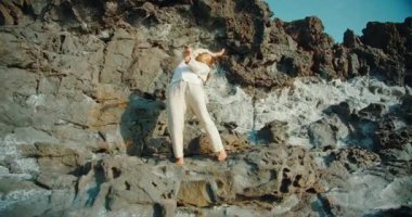 Gündüz vakti kayalık uçurumda çağdaş dans eden bir kadın..