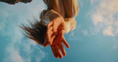 Dans gösterisi sırasında kayalık kenar tarafından çerçevelenmiş eller gökyüzüne uzanır..