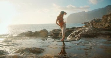 Gün batımında çıplak ayakla dans eden kadın Tenerife 'de okyanus ve uçurum manzaralı..