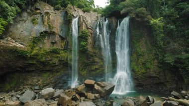 Kosta Rika 'nın tropikal ormanlarındaki kayalık uçurumlardan akan güçlü şelaleler.