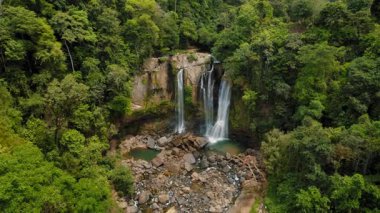 Kosta Rika 'da yoğun yeşil ormanlarla çevrili Nauyaca şelalesinin insansız hava aracı görüntüsü.