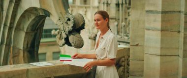 Kadın, İtalya 'daki Milan Katedrali' nde elinde şehir haritası ve İtalyan bayrağıyla taştan bir korkuluğun yanında duruyor..