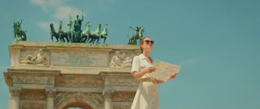 İtalya 'nın Milano kentindeki kemer heykelinin önünde turistik yerleri keşfeden kadın harita okuyor..