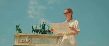 İtalya, Milano 'daki Arco della Pace anıtının yanında bir şehir haritası tutan kadın..