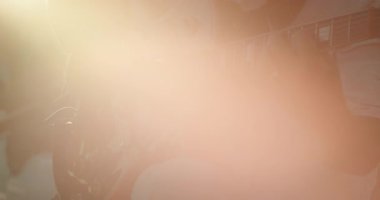 Açık hava gösterisinde gitar çalan bir adamın üzerinde puslu bir güneş parlıyor..