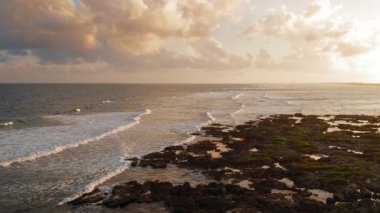 Dalgalar ve Meksika 'nın Yucatan yarımadasındaki kayalık kıyı şeridi ile okyanusun üzerinde gün batımı.