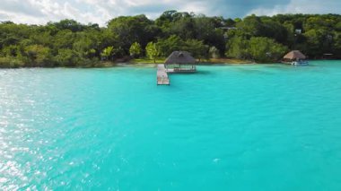Bacalar Lagoon Mexico 'daki turkuaz su üzerindeki ahşap iskelede manzaranın keyfini çıkaran kadın..