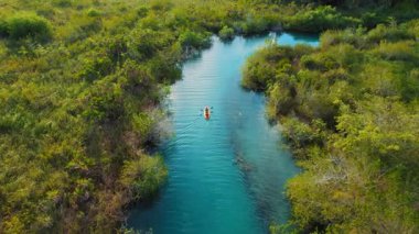 Yoğun bitki örtüsü Bacalar ile çevrili açık mavi kanalda süzülen kano..