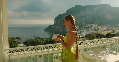 Bir kadın Capri İtalya ve deniz manzaralı sabah kahvesinin tadını çıkarıyor..