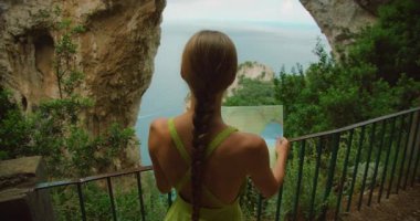 Tourist reading a map at Arco Naturale natural rock arch viewpoint in Capri Italy.