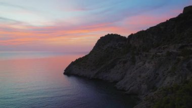 Yunanistan 'ın Kefalonya adasındaki kayalık kayalıkların ve sakin denizin üzerinde gün batımı.