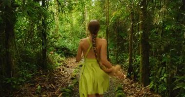Kosta Rika 'nın canlı tropik yeşillikleri arasında bir kadın turist neşeyle orman yolunda dönüyor..