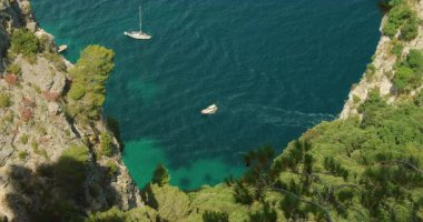 Tekneler, Capri İtalya 'daki kayalık kayalıklar arasında derin mavi yaz sularında ilerler..