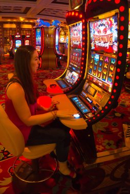 LAS VEGAS - MAY 06, 2016: Concentrated girl playing slot machines in the Excalibur Hotel and Casino clipart