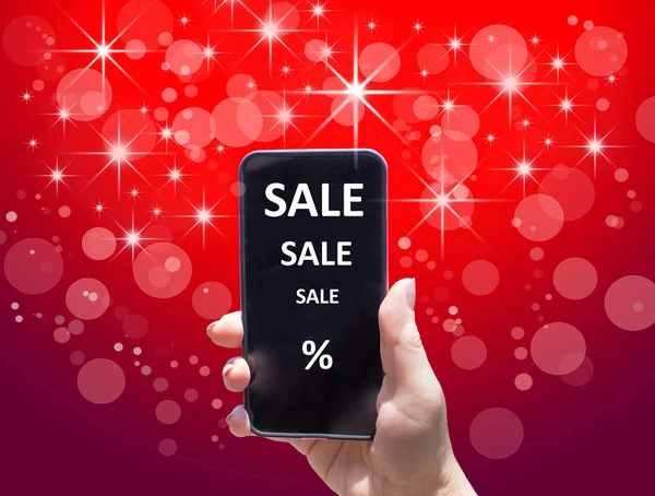 The phone with text SALE in female hand on the red background