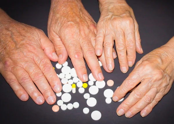 The old female and male hands with pills on black background