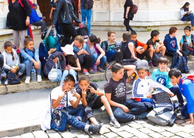 Lyon, Fransa - 16 Haziran 2016: Grup eski şehir Katedrali basamaklarında oturan çocuk
