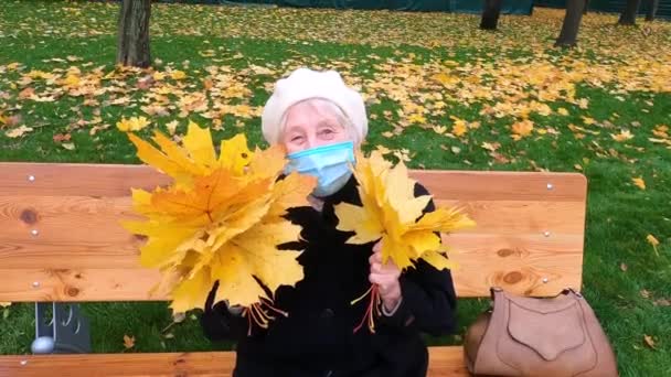 Eine Ältere Frau Schutzmaske Und Einem Strauß Herbstblätter Amüsiert Sich — Stockvideo