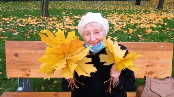 Starsza Kobieta Masce Ochronnej Bukiet Jesiennych Liści Bawi Się Jesiennym — Wideo stockowe