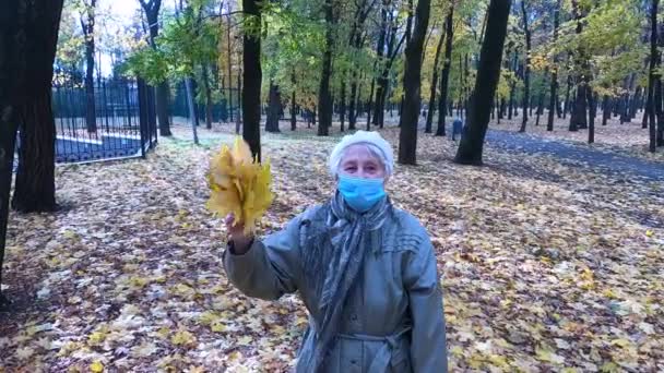 Eine Ältere Frau Schutzmaske Und Einem Strauß Herbstblätter Amüsiert Sich — Stockvideo