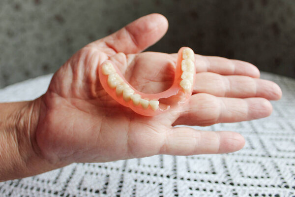 flexible nylon denture on male hand. Removable dentures flexible, devoid of nylon, hypoallergenic exempt from monomer