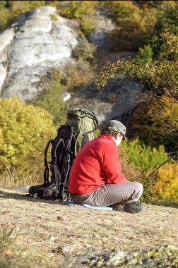 Kırım, Ukrayna - 27 Eylül 2009: Dağın tepesinde oturan yürüyüşçü. Kırım 'daki dağlar güneşli yaz gününde.