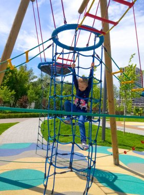 Mavi gökyüzüne karşı macera halat parkına tırmanan kız.