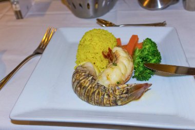 Soslu ıstakoz ve beyaz tabakta sebze..